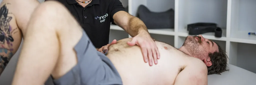 Fyzioterapeut provádí manuální terapii na hrudi pacienta.