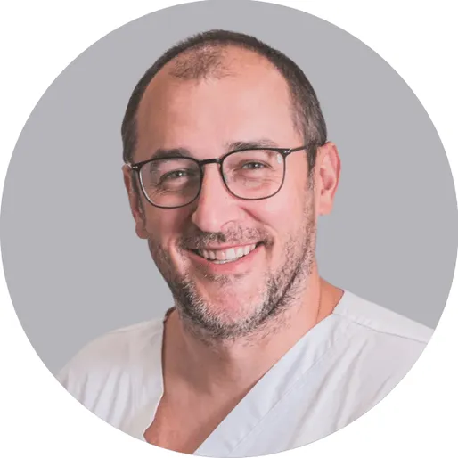 Lékař v bílém obleku se usmívá na pozadí.