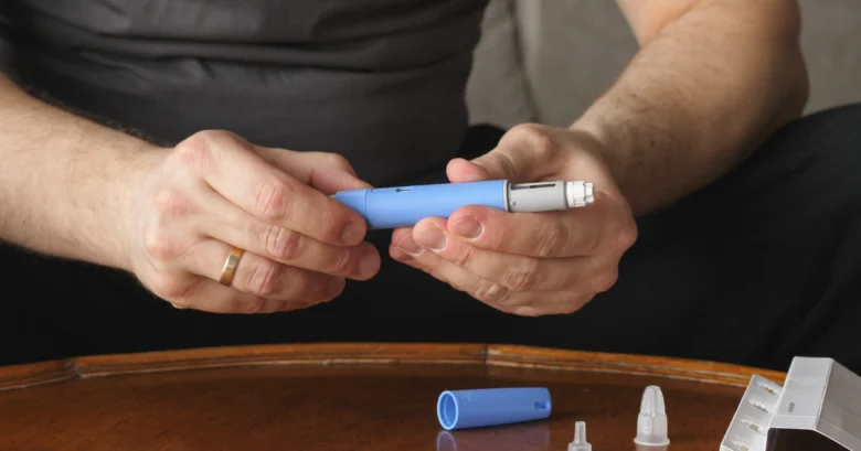 Muž drží modrou injekční tuži na diabetika.