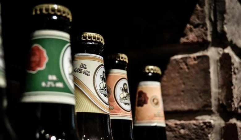 Řada pivních lahví s viditelným obsahem alkoholu na štítcích.
