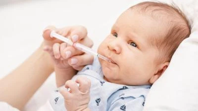 Novorozenec dostává vitamín K pipetou do úst