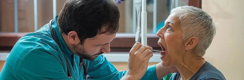 Lékař vyšetří ústní dutinu pacienta pomocí nástroje.