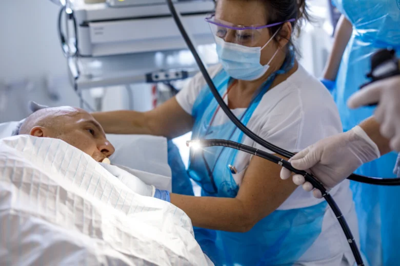 Lékař provádí gastroskopii pacientovi pomocí endoskopu v nemocničním prostředí.