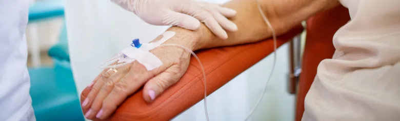 Zdravotník aplikuje infuzi na ruku pacienta v ordinaci.