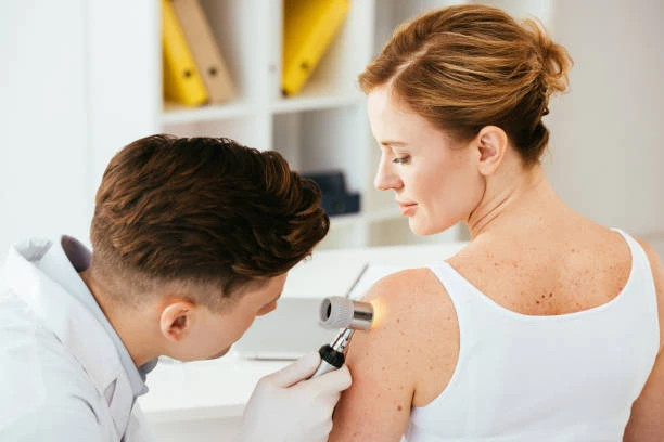 Dermatolog zkoumá znaménko na kůži pomocí daskopu.