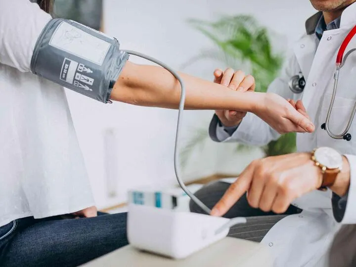 Lékař měří krevní tlak pacienta pomocí digitálního tlakoměru.