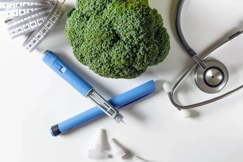 Modrá injekční tužka na diabetika vedle brokolice.
