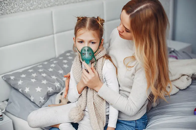 Dívka s maskou na inhalační léčbu suchého dráždivého kašle.