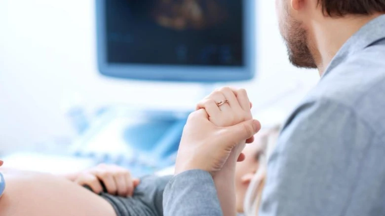 Muž drží ruku těhotné ženy při ultrazvukovém vyšetření.