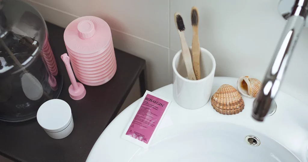 Růžové intimní hygienické produkty na koupelnovém pultu.