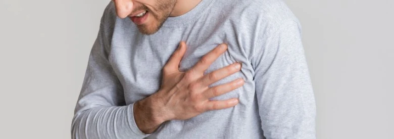 Muž drží ruku na hrudi kvůli bolesti srdce.