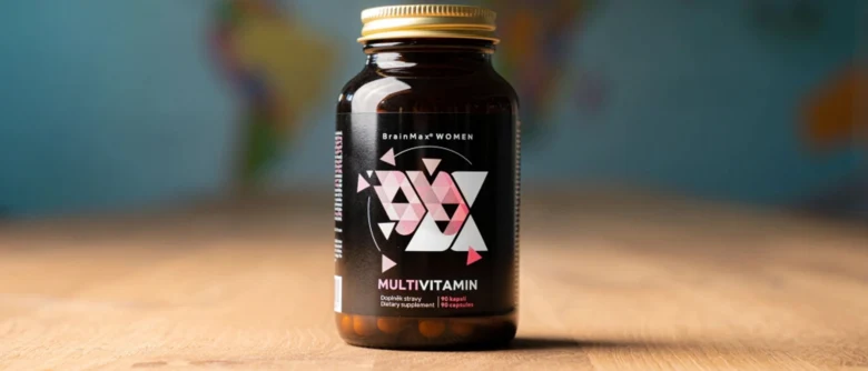 Fialová lahvička s vitamíny pro ženy na dřevěné desce.