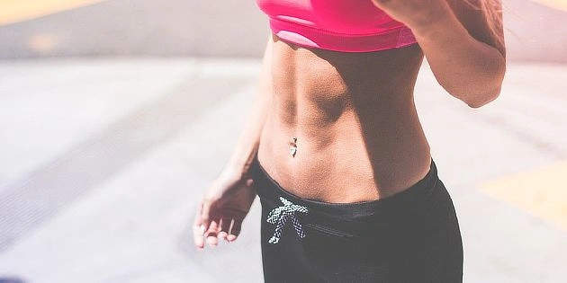 Žena v sportovním oblečení s viditelným břišním svalstvem.