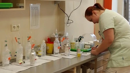 Sestra připravuje chemoterapii na laboratorním stole s flakony.