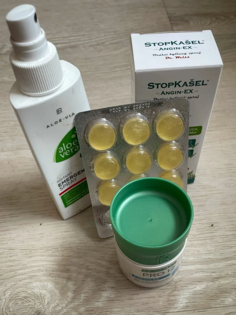 Soubor léků na bolest v krku včetně pastilek a spreje.