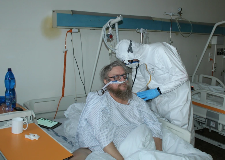 Pacient v nemocničním lůžku s lékařem ve výbavě pro ochranu před viry.