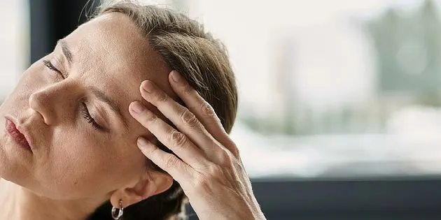 Žena s bolestí hlavy, která může souviset se symptomy roztroušené sklerózy.