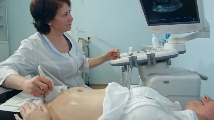 Ultrazvukové vyšetření břicha těhotné ženy v klinickém prostředí.