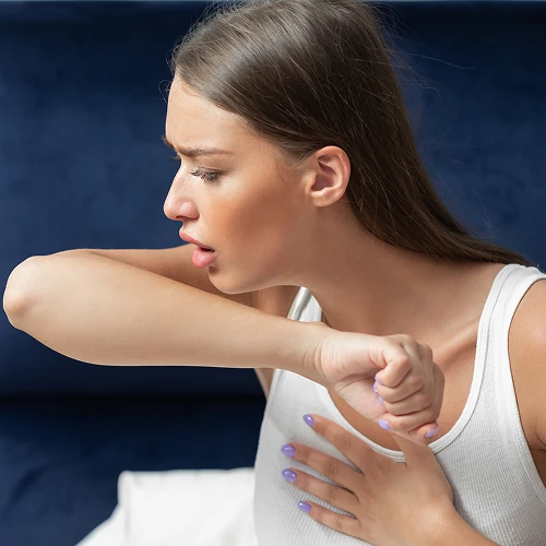 Woman coughing on arm