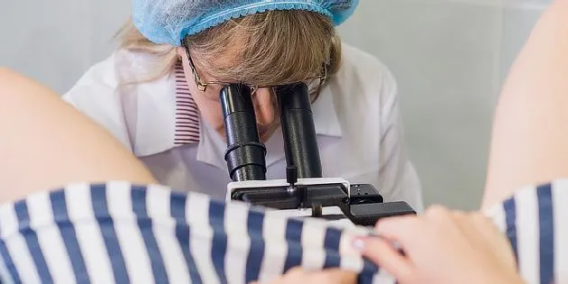 Lékař zkoumá vzorek tkáně pod mikroskopem při preventivním vyšetření.