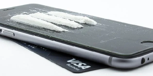 Bílý prášek na displeji mobilního telefonu jako amfetamin.