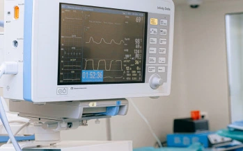 Medicínský monitor v nemocničním prostředí zobrazující životní signály.