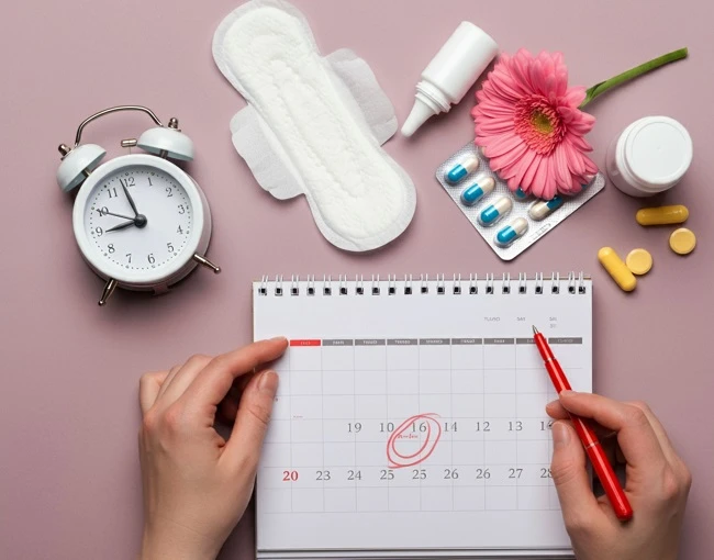 Ruce označují kalendář s menstruačním cyklem vedle hygienických potřeb.