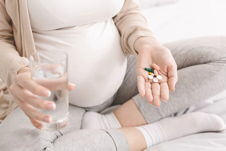 Těhotná žena s tabletami ve vodě, ne cholesterol.