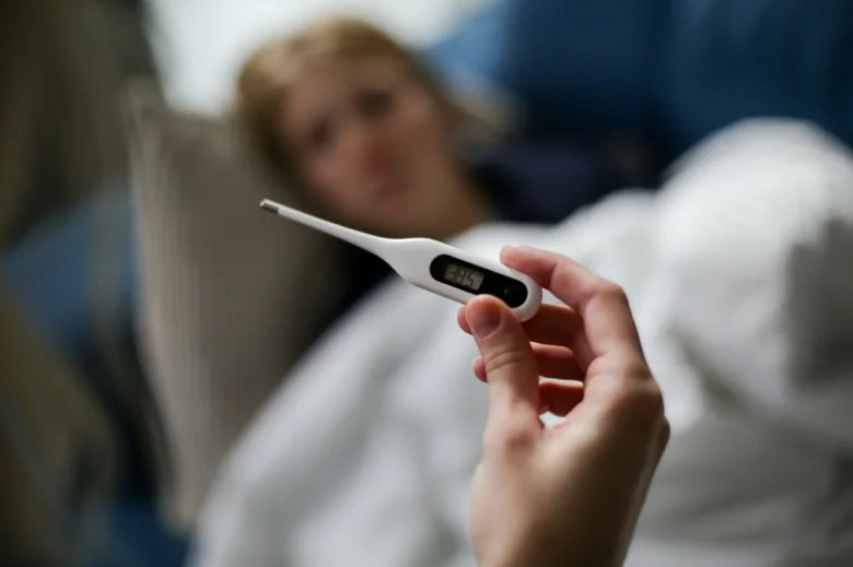 Digitální teploměr ukazuje zvýšenou teplotu u nemocného člověka.
