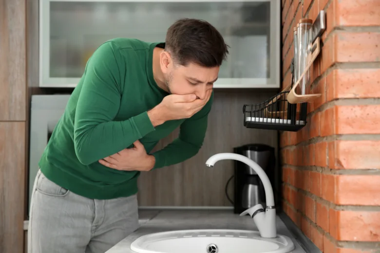 Muž zažívá nevolnost u dřezu v kuchyni