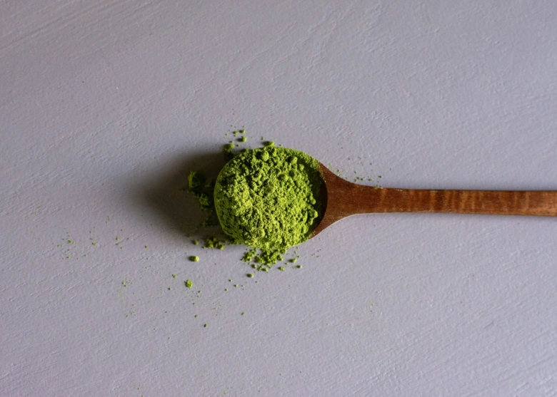Dřevěná lžička s jemným zeleným práškem čaje Matcha.