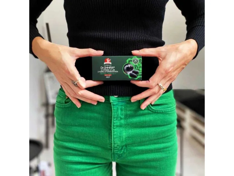 Žena drží krabičku s prebiotiky před pasem.