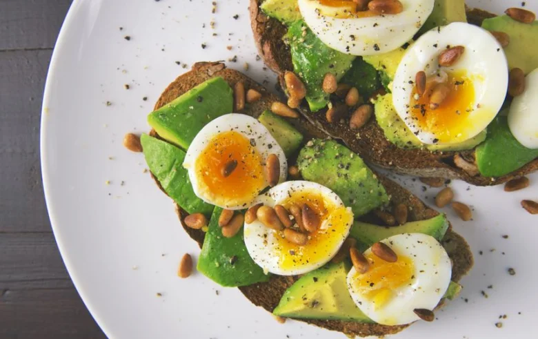 Avokádový toast s vejci na bílém talíři.