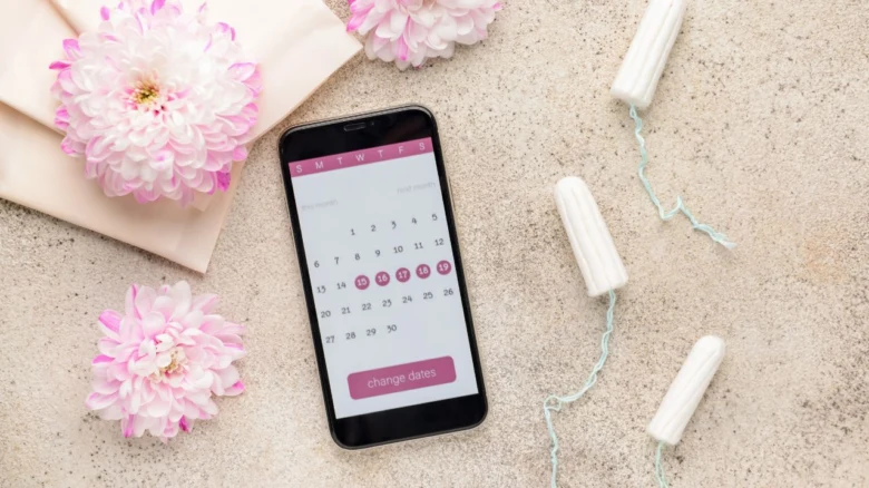 Telefon s aplikací pro sledování menstruačního cyklu mezi tampóny.