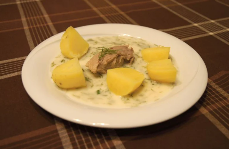 Jídlo s bramborami a masem v smetanové omáčce na talíři.
