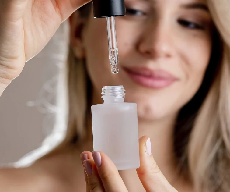 Žena s pipetou aplikuje glycerol z lahvičky na kůži.