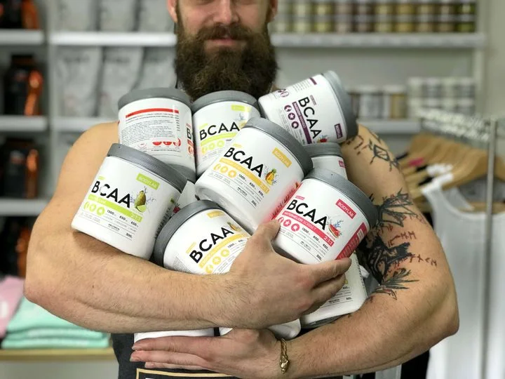 Muž drží v náručí více tubů s doplňkem BCAA.