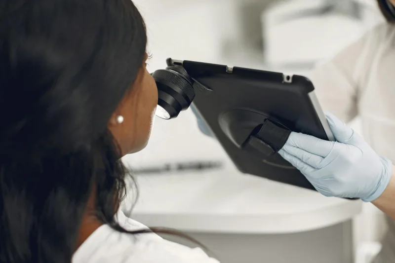 Dermatolog zkoumá kůži pacienta pomocí digitálního diagnostického nástroje v ordinaci.