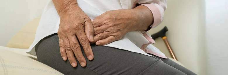Elderly person holding hip in pain