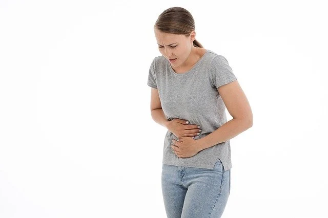Žena drží břicho v bolesti při zánětu ledvin.