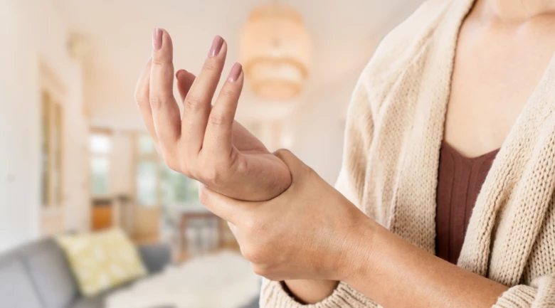 Žena drží ruku v bolesti jako příznak neuropatie