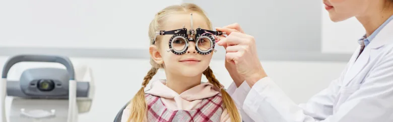 Děvčinka zkoumá oči s brýlemi na refrakci u optometristy.