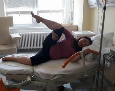 Těhotná žena se protahuje na lůžku v nemocničním prostředí.