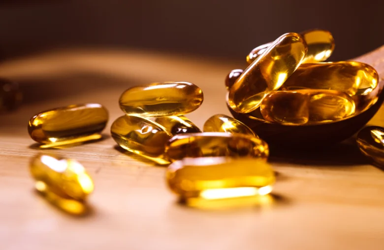 Žluté tobolky s vitamínem D na dřevěném povrchu.