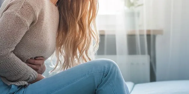 Žena drží břicho v bolesti při menstruačních křečích.