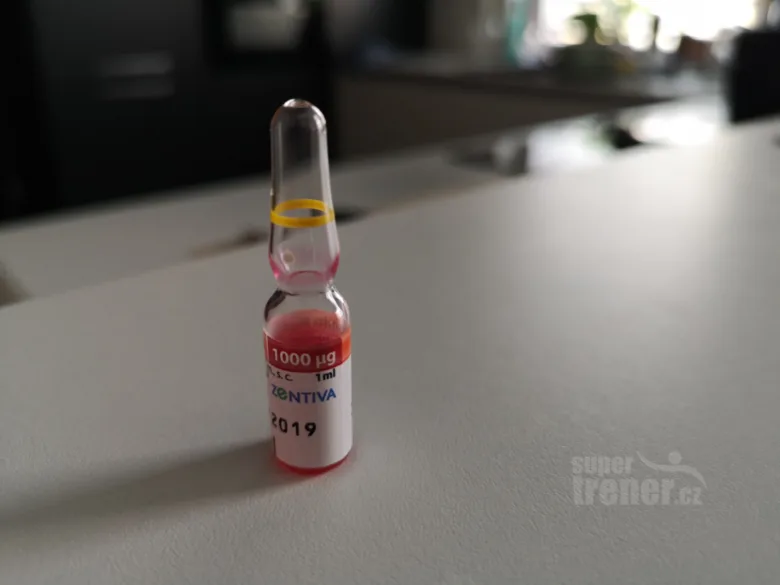 Skleněná ampule s červenou tekutinou, vitamínem B12.