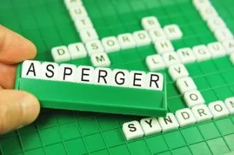 Ruka drží kostičky s písmenem Asperger v křížovce.