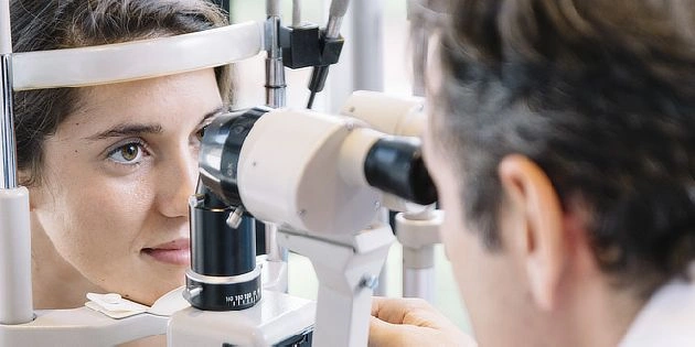 Žena podléhá vyšetření oka pomocí štěrbinové lupy u lékaře.