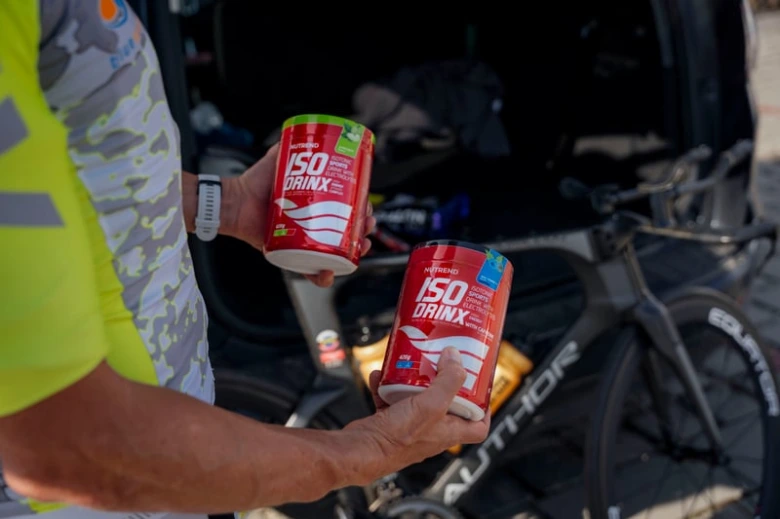 Cyklista drží nápoje na rehydrataci vedle kola v autě.