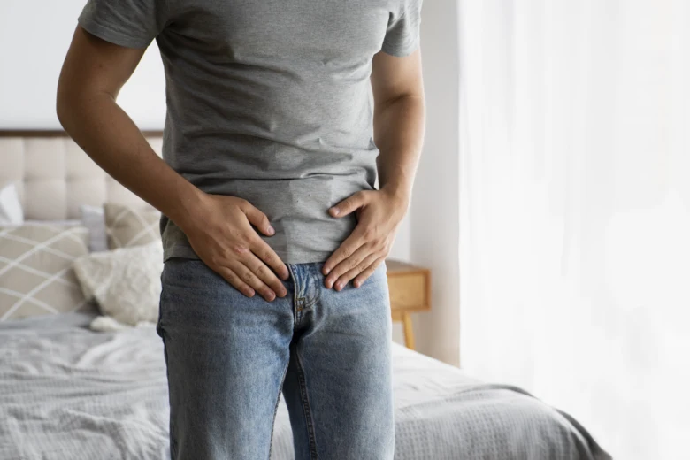 Muž drží ruce na dolním břiše kvůli bolesti prostaty.